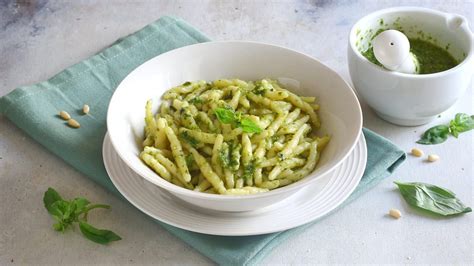 Primo piano di un piatto di pasta al pesto su un tavolo rustico