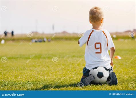 Bambino che piange in campo da calcio con il pallone vicino